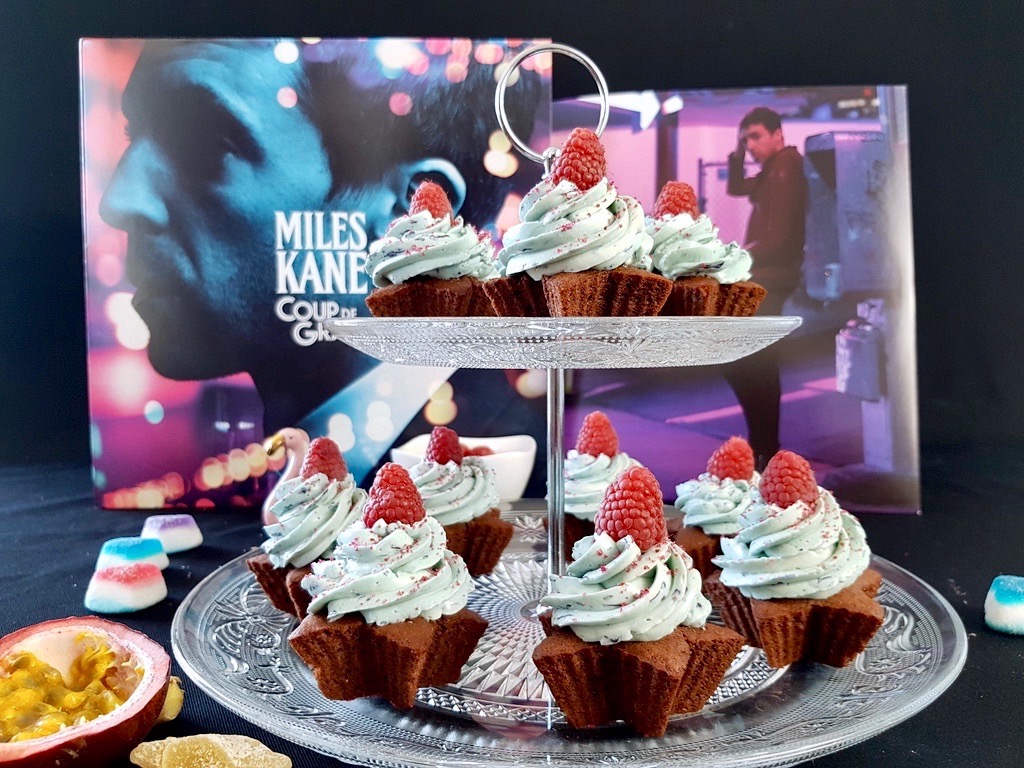 Chocolate cupcakes topped with butterfly pea tea blue buttercream and raspberry next to Miles Kane vinyl record