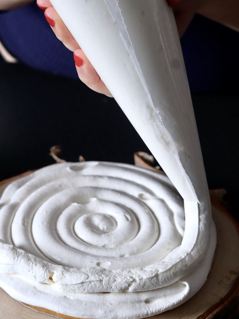 Piping whipped cream on pavlova