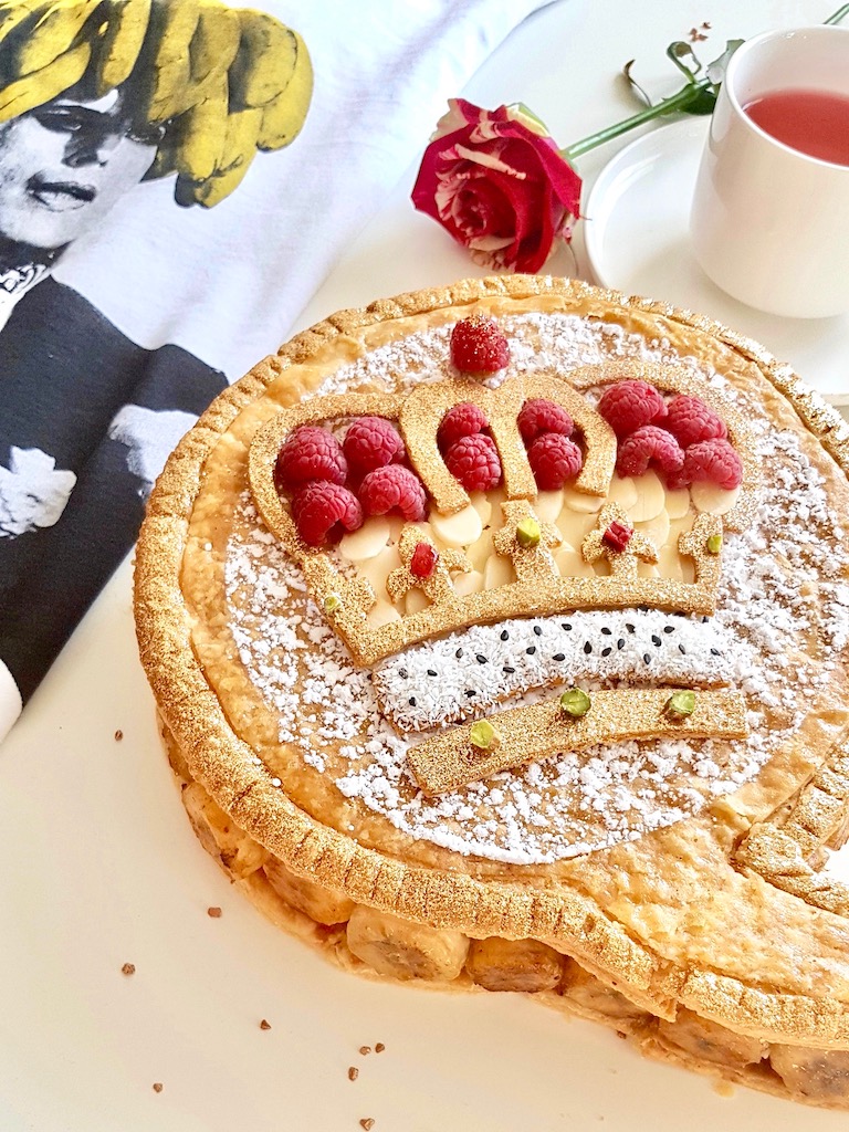 Galette des rois topped with puff pastry crown design almonds and raspberries next to Freddie Mercury Tshirt