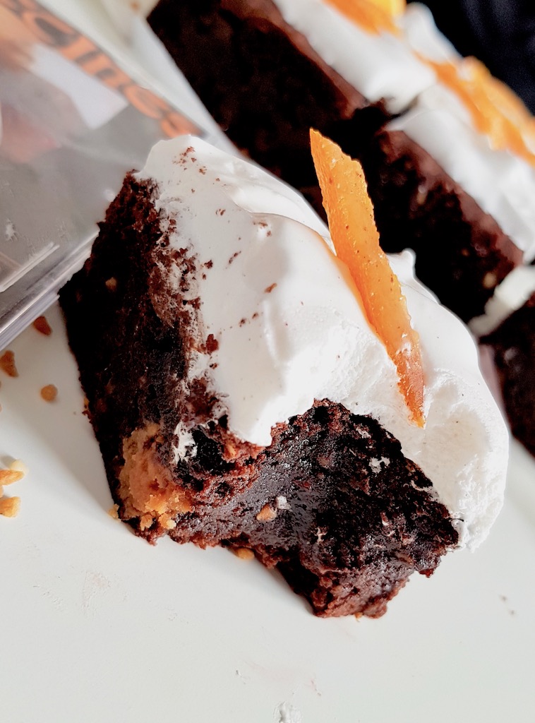 Bitten chocolate brownie covered with marshmallow and candied orange peel