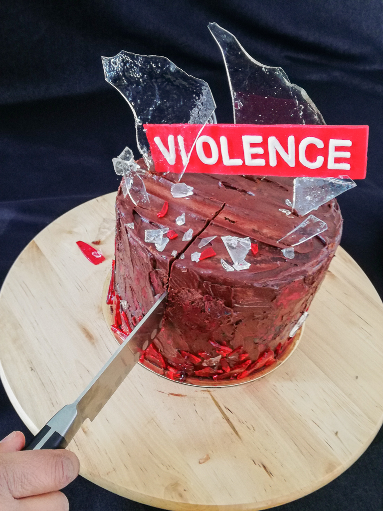 Knife cutting chocolate layer cake with edible glass