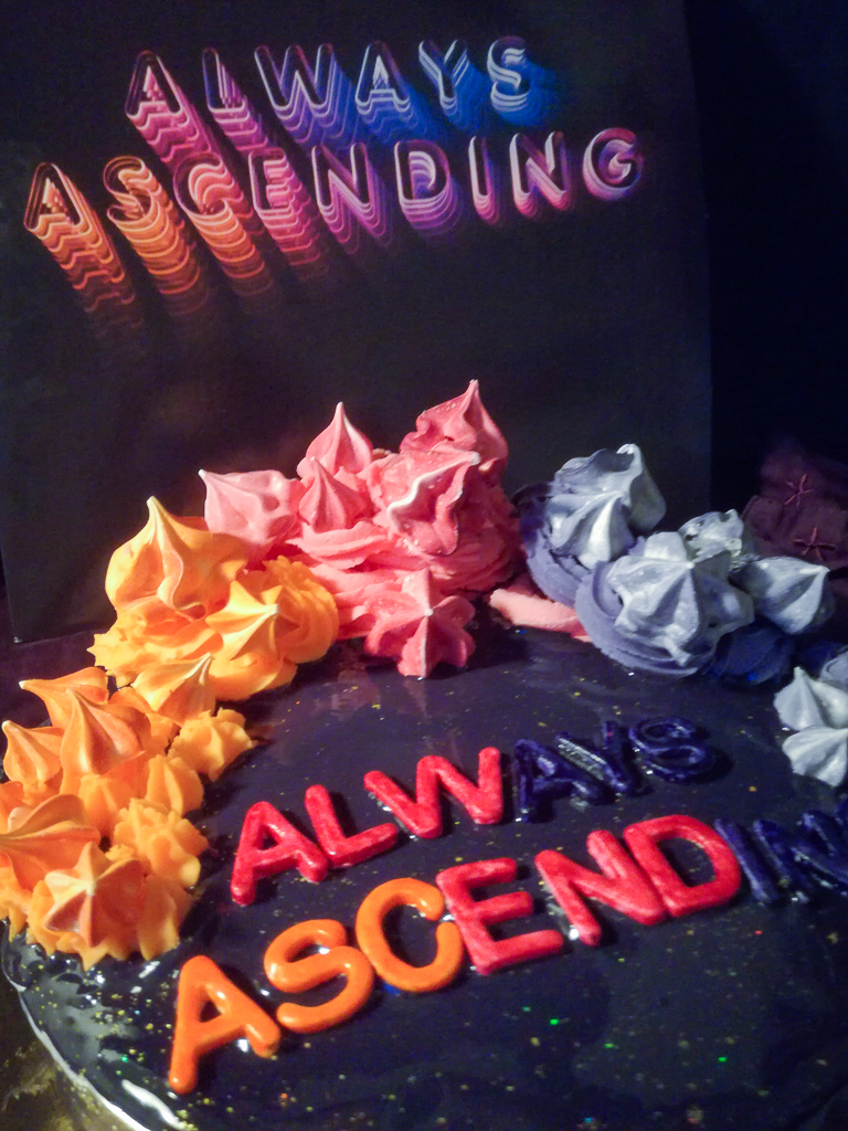 Mirror glaze cake topped with meringues and buttercream close up next to Franz Ferdinand Always Ascending vinyl record