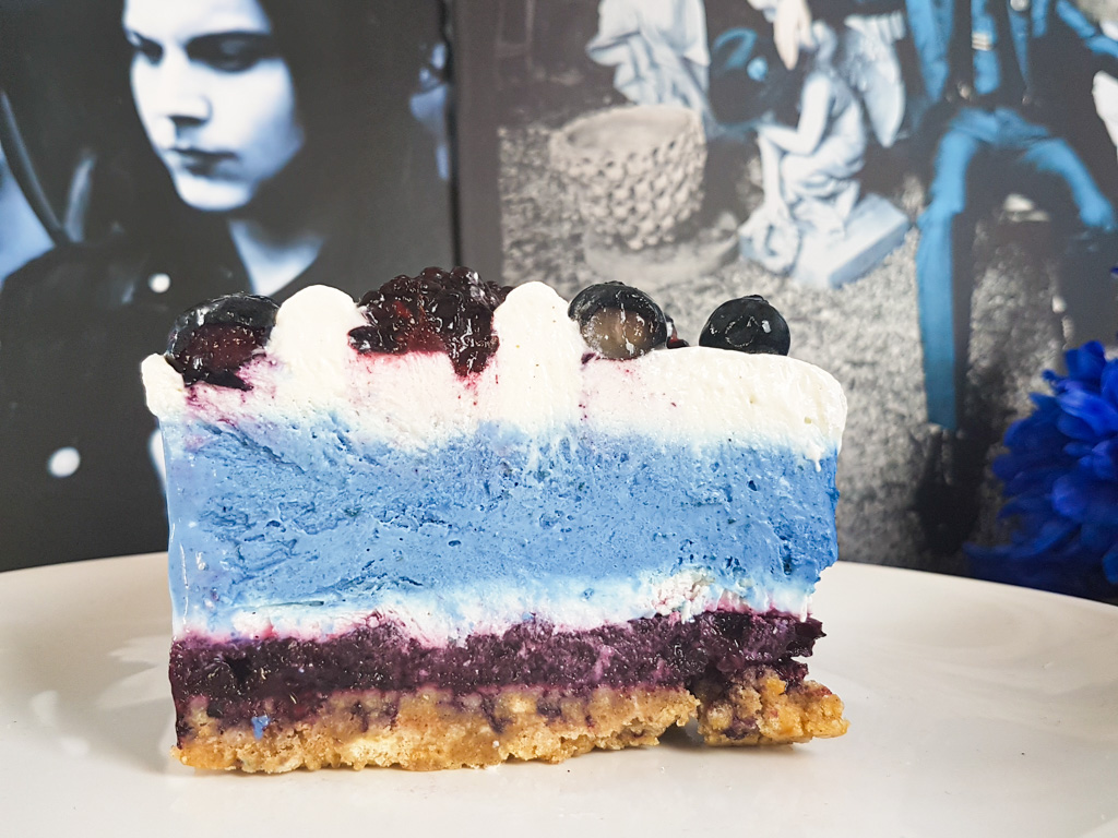 Slice of graphic blue and white cheesecake topped with blueberries and blackberries next to Jack White Blunderbuss Lazaretto vinyl records