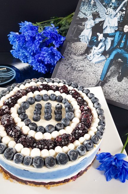 Graphic blue and white cheesecake topped with blueberries and blackberries next to Jack White Lazaretto vinyl and blue flowers