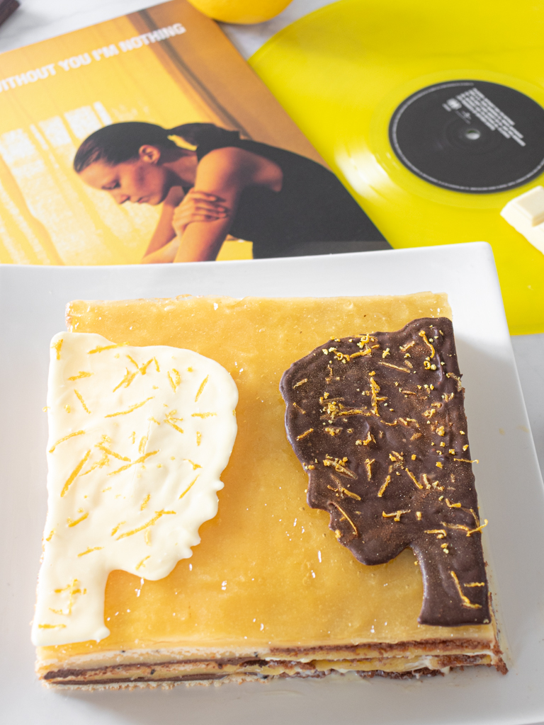 Lemon opera cake cut with chocolate faces next to Placebo Without You I'm Nothing vinyl record