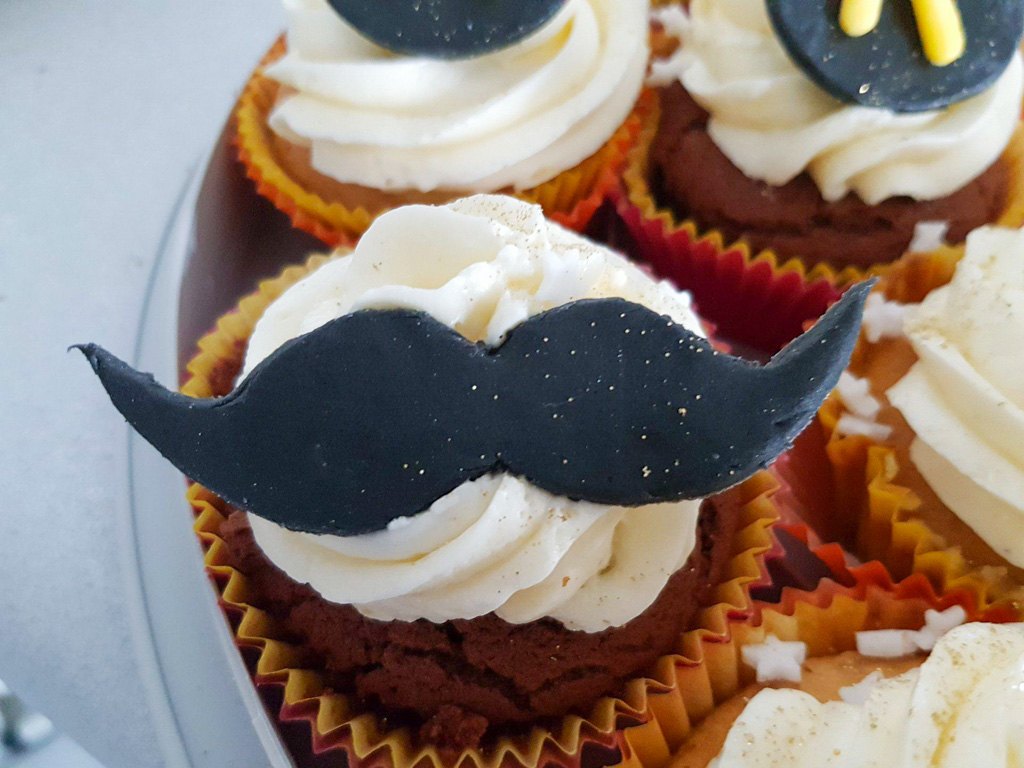 Cupcake topped with buttercream and black sugar paste moustache