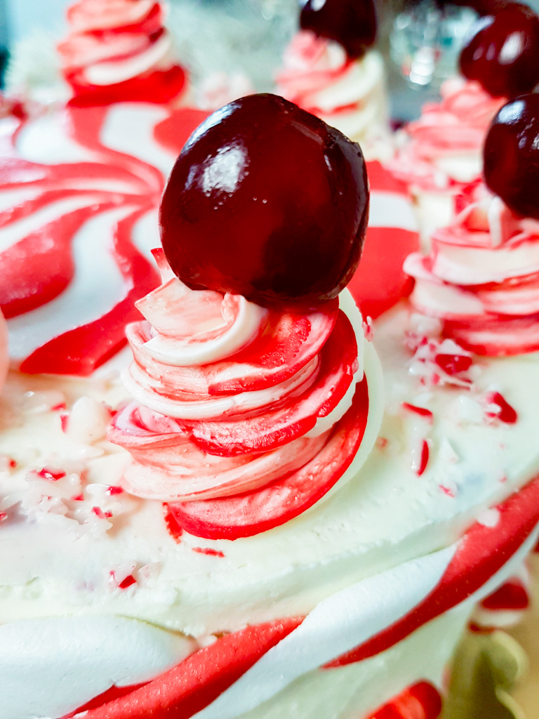 Striped red and white swiss meringue buttercream topped with candied cherry