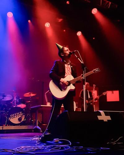 Neil Hannon on stage wearing a party hat with The Divine Comedy
