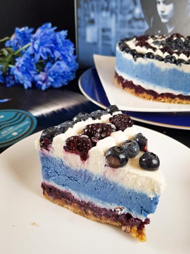 Slice of graphic blue and white cheesecake topped with blueberries and blackberries next to Jack White Blunderbuss vinyl