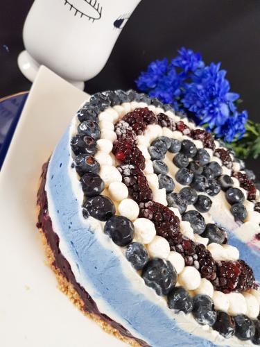 Graphic blue and white cheesecake topped with blueberries and blackberries