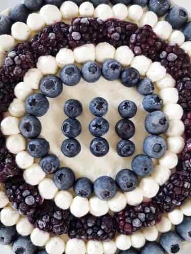 Graphic blue and white cheesecake topped with blueberries and blackberries view from top