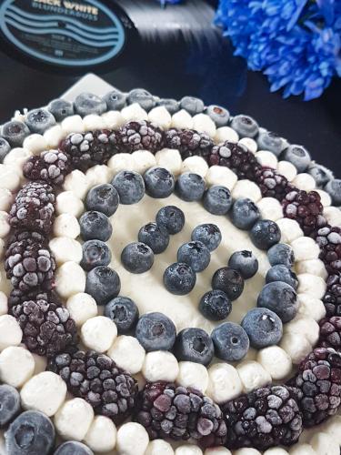 Graphic blue and white cheesecake topped with blueberries and blackberries