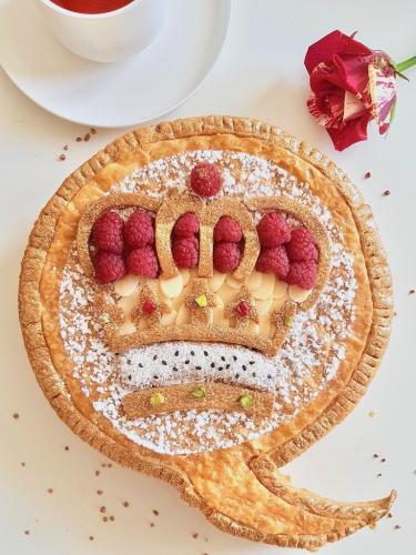 Galette des rois topped with puff pastry crown design almonds and raspberries