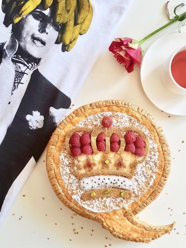 Galette des rois topped with puff pastry crown design almonds and raspberries next to Freddie Mercury Tshirt
