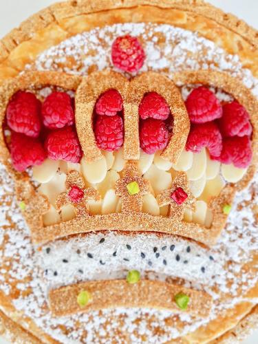 Galette des rois topped with crown design almonds and raspberries close up