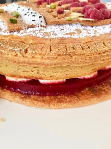Galette des rois topped with crown design filled with bananas and rapsberry cream close up