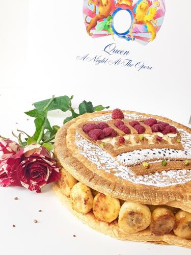 Galette des rois topped with crown design filled with caramelized bananas next to Queen A Night At The Opera vinyl record